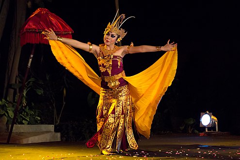 A dancer with her skirt in her arms, forming the "wings" of the bird of paradise she's emulating