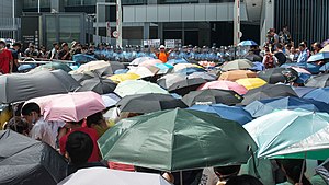 Protesters shielding themselves from tear gas and water cannons with umbrellas
