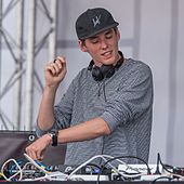 A shot of Lost Frequencies at his turntables, wearing a grey cap and a black-white T-shirt.