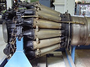 de Havilland Goblin with sixteen straight-through combustion chambers. Each consists of a flame tube enclosed in a pressure-tight outer casing. They are connected by tubes which balance the pressure and propagate the flame during start from the two tubes with igniters one of which is shown on a top tube.[88]