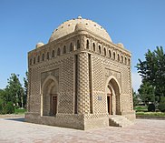 A cuboid building with a dome, in a greenery-enclosed plaza.