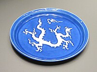 Yuan dynasty dish with a white dragon and pearl design on a monochrome blue background