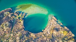 A vertical shot of a turquoise-blue lake