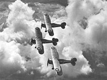 Photographie noir et blanc de trois biplans en formation dans le ciel. La cocarde de la RAF est visible sur l'aile supérieur, à chaque bout d'aile.