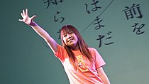 A smiling, waving Mari Okada