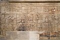 King Taharqa and the gods of Thebes. Standing on the left, he offers "a white loaf" to his father Amun-Re, who is accompanied by Mut, Khonsu and Montu, Kawa shrine.[60]