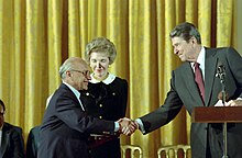 Ronald Reagan shaking hands with Milton Friedman giving him the Presidential Medal of Freedom