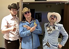 Three Caucasoid men in cowboy hats are posing; they are all facing the camera, depicted from the hips up.