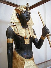 Gilded statue wearing a headdress with a model cobra
