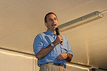 Man speaking with a microphone in his right hand