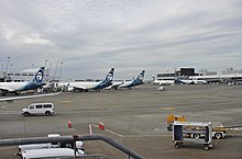 Five aircraft can be seen in this photo. The jets are either parked at or adjacent to a terminal, with some connected to the building by jet bridges