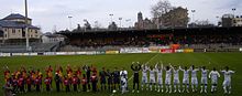 Photo de la présentation des équipes en début de match, les rouge et jaune à gauche contre les blancs à droite.