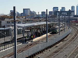 A light rail station next to a railway line in an urban area