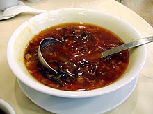 Un bol de soupe rouge avec des morceaux.