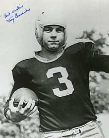 A black and white portrait of Canadeo in his football uniform and holding a football. The photo is signed by Canadeo.