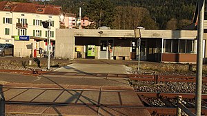 Station shelter with a bench, ticket machine next to a railway crossing