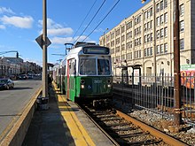 A light rail train at a surface station in the median of an urban street