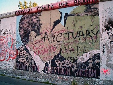 The Berlin wall has become a Mecca for graffiti writers. Featured here is an image of Leonid Brezhnev and Erich Honecker making out. The words at the top read "God! help me stay alive"; and continue at the bottom "Among this deadly love." This image was used in this magazine article