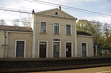 Photographie en couleurs d'un bâtiment le long de voies ferrées.