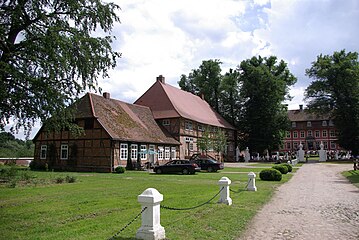 Zufahrt auf das Schloss mit barockem Tor, links das Brauhaus mit Anbau