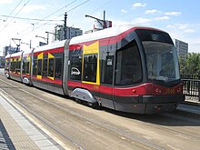 Tram in red and grey livery with irregular yellow shapes around some windows