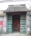 A folding security gate has been installed outside the once-elegant gate of the siheyuan