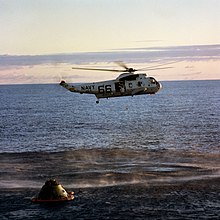 Photographie couleur d'un hélicoptère au-dessus de la capsule d'Apollo 10 flottant sur l'océan.