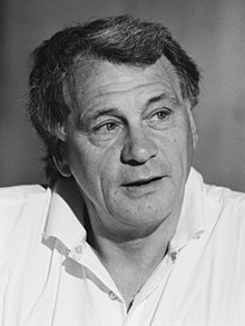 Photographie en noir et blanc. Portrait de Bobby Robson en chemise blanche, regardant vers sa gauche.