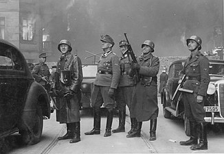 NARA copy #43, IPN copy #43 The leader of the grand operation Second from left Stroop; background either Karl Kaleske [pl] (Stroop's adjutant) or Erich Steidtmann; 2nd from right Heinrich Klaustermeyer; far right Josef Blösche and others at Nowolipie 64 / Smocza 1 intersection