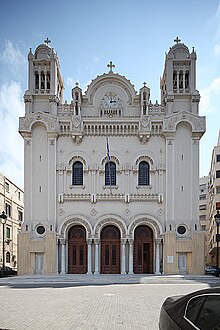 Cathedral facacde with three doors, three windows, and two bell towers.