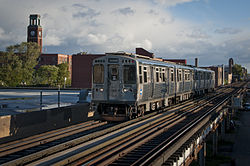 A Chicago 'L' train passes through Ravenswood with the tower of the former J.C. Deagan Company factory in the background.