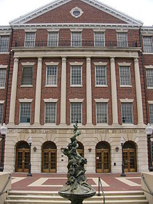 A large Georgian-era style building complete in red brick, classical columns and a statue in front