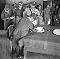 Baba signs the surrender document in Labuan, British Borneo, being watched by Australian Major General George Wootten and other Australian units on 10 September 1945