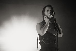 black and white photo of a young Asian-American woman with shoulder-length black hair singing.