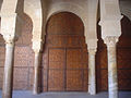 Vue centrée sur l'une des portes en bois sculpté de la salle de prière. Sa décoration comprend des moulures et des motifs géométriques simples (rectangles, carrés, etc.).