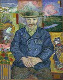 Portrait of a man of a bearded man facing forward, holding his own hands in his lap; wearing a hat, blue coat, beige collared shirt, and brown pants; sitting in front of a background with various tiles of far eastern and nature-themed art.