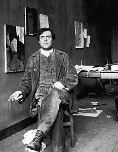 Photographie d'Amedeo Modigliani assis dans son atelier d'artiste à côté du Portrait de Beatrice Hastings, vers 1918.