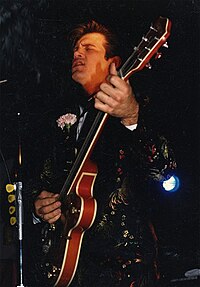 a man is playing a red guitar and singing in a microphone.