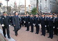 Macri, in an overcoat, walks down a line of young police officers