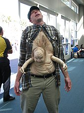 A photo of a cosplayer dressed as George with his mutant brother Kuato situated on his stomach