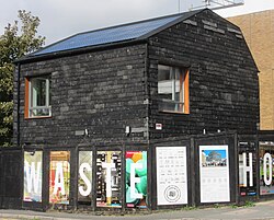 Black-tiled two-storey building with solar panels on the roof