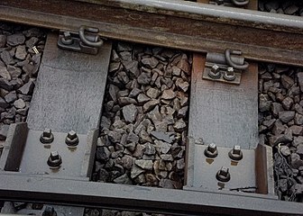Traditional railway track showing ballast, part of sleeper and fixing mechanisms
