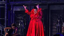 Photograph of a person on a stage wearing a red outfit