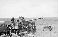 Black and white picture of a Panzer VI being replenished with ammunition in an open, treeless field.