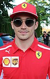 Charles Leclerc wearing a scarlet red Ferrari T-shirt and sporting black sunglasses
