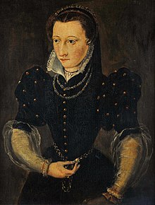 Hip-high portrait of a woman wearing a dark blue dress with a white standup collar and elbow-length sleeves