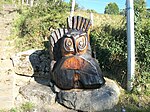 Un grand hibou sculpté en bois à l'entrée du village