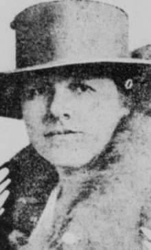 A white woman wearing a plain brimmed hat and a fur over her shoulders