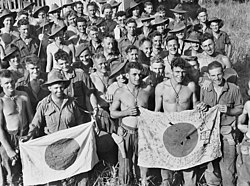 Men wearing military uniforms including jungle greens and slouch hats, display Japanese flags