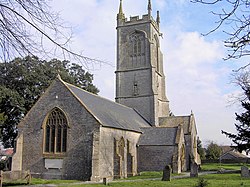 Stone building with prominent square tower. In the foreground are gravestones.